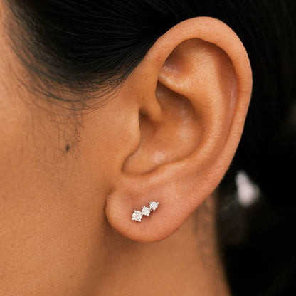 Close-up of an ear wearing a diamond earring with a blurred background