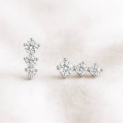 Pair of earrings with clear gemstones on a light pink background