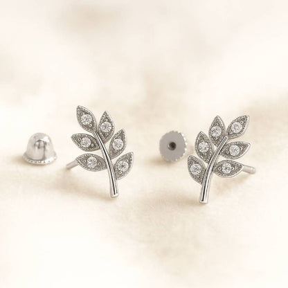  leaf-shaped earrings with gemstones on a beige background