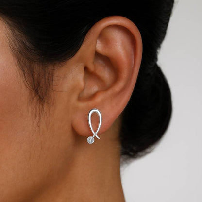 earring with a small gemstone worn by a person on a plain background