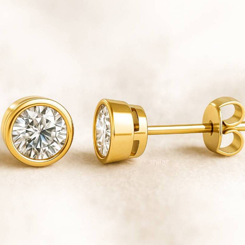 Gold earrings with clear gemstones on a beige background