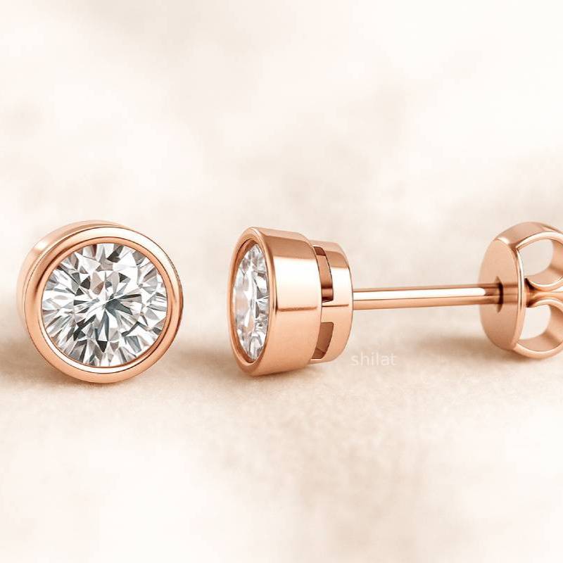 Rose gold earrings with clear gemstones on a beige background
