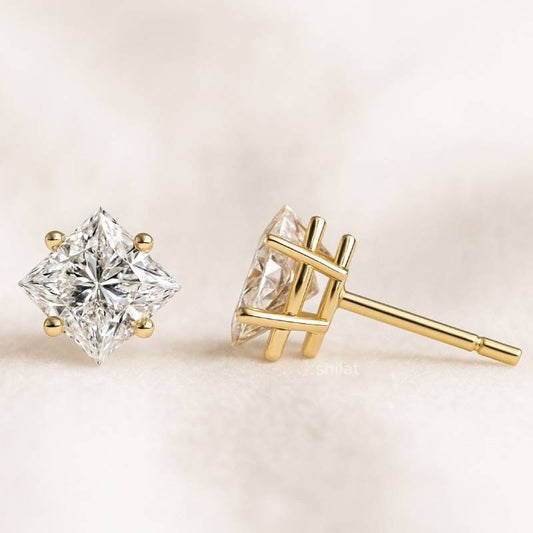 Gold diamond earrings on a light beige background