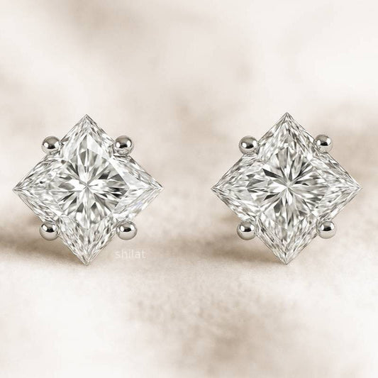 Pair of diamond earrings on a soft beige background