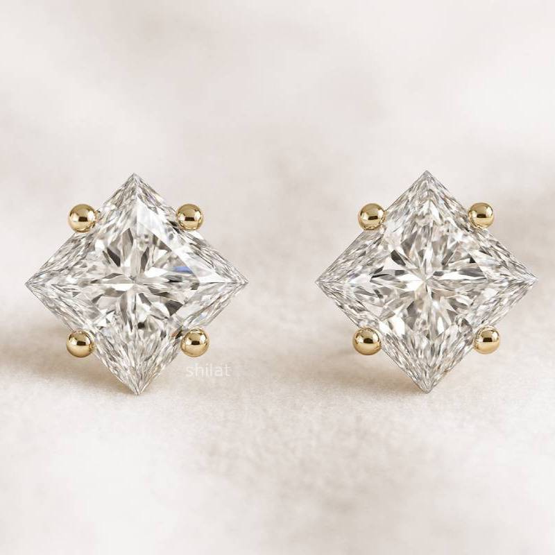 Pair of diamond stud earrings with gold accents on a light background