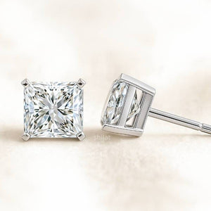 Two diamond earrings on a light beige background