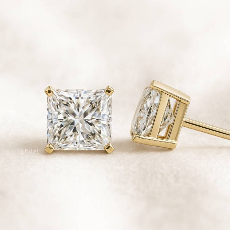 Two diamond earrings on a light beige background