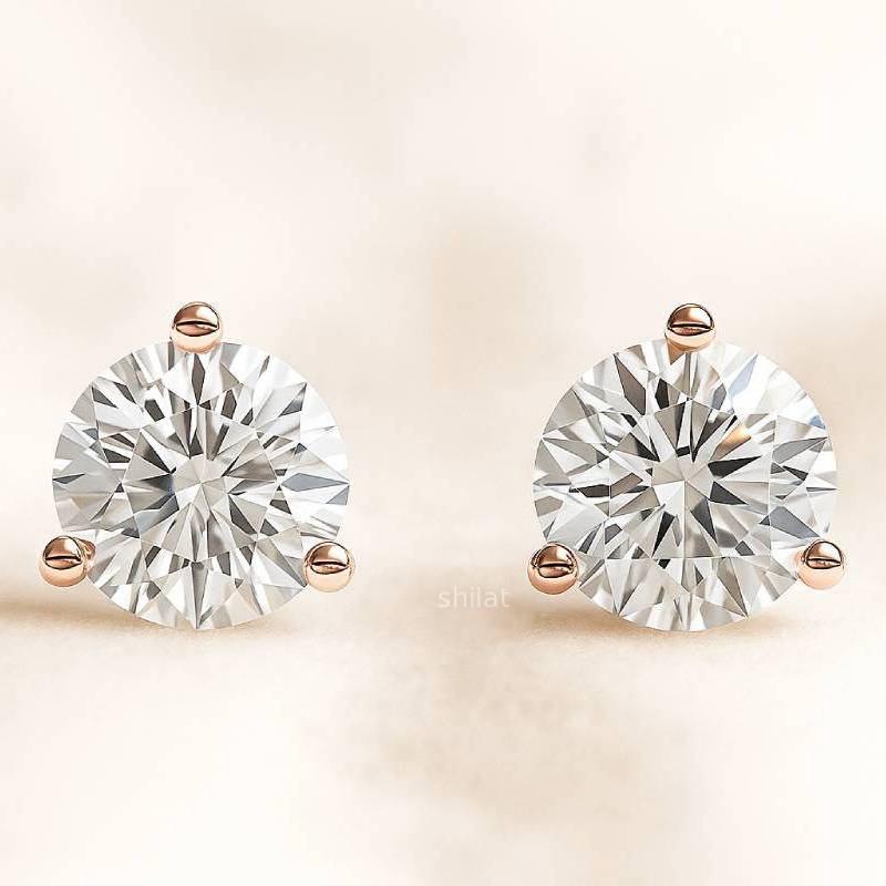 Pair of diamond stud earrings on a beige background