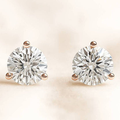Pair of diamond stud earrings on a beige background
