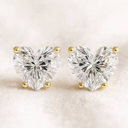 Heart-shaped diamond earrings with gold accents on a light background