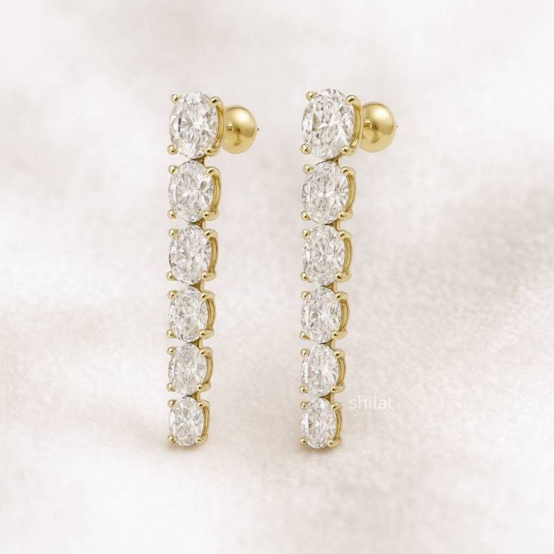 Gold earrings with clear gemstones on a light pink background