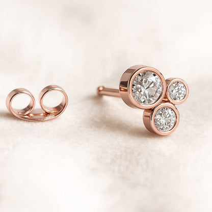 Rose gold earrings with clear gemstones on a light background
