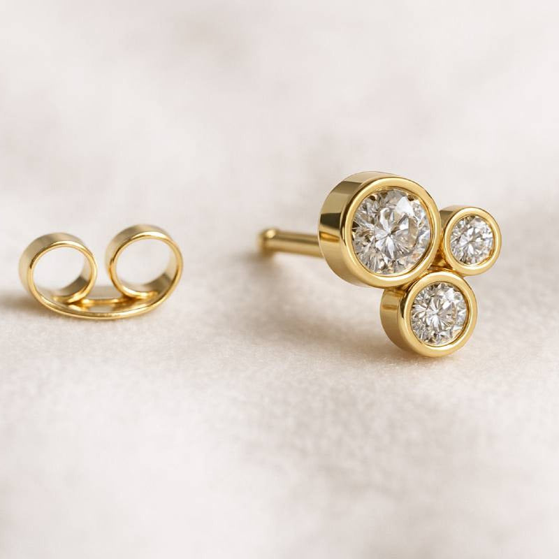 Gold earrings with diamond studs on a light background