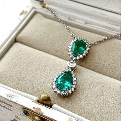 Emerald and diamond pendant necklace on a textured surface