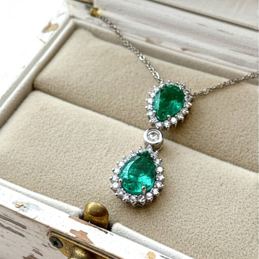 Emerald and diamond pendant necklace on a textured surface