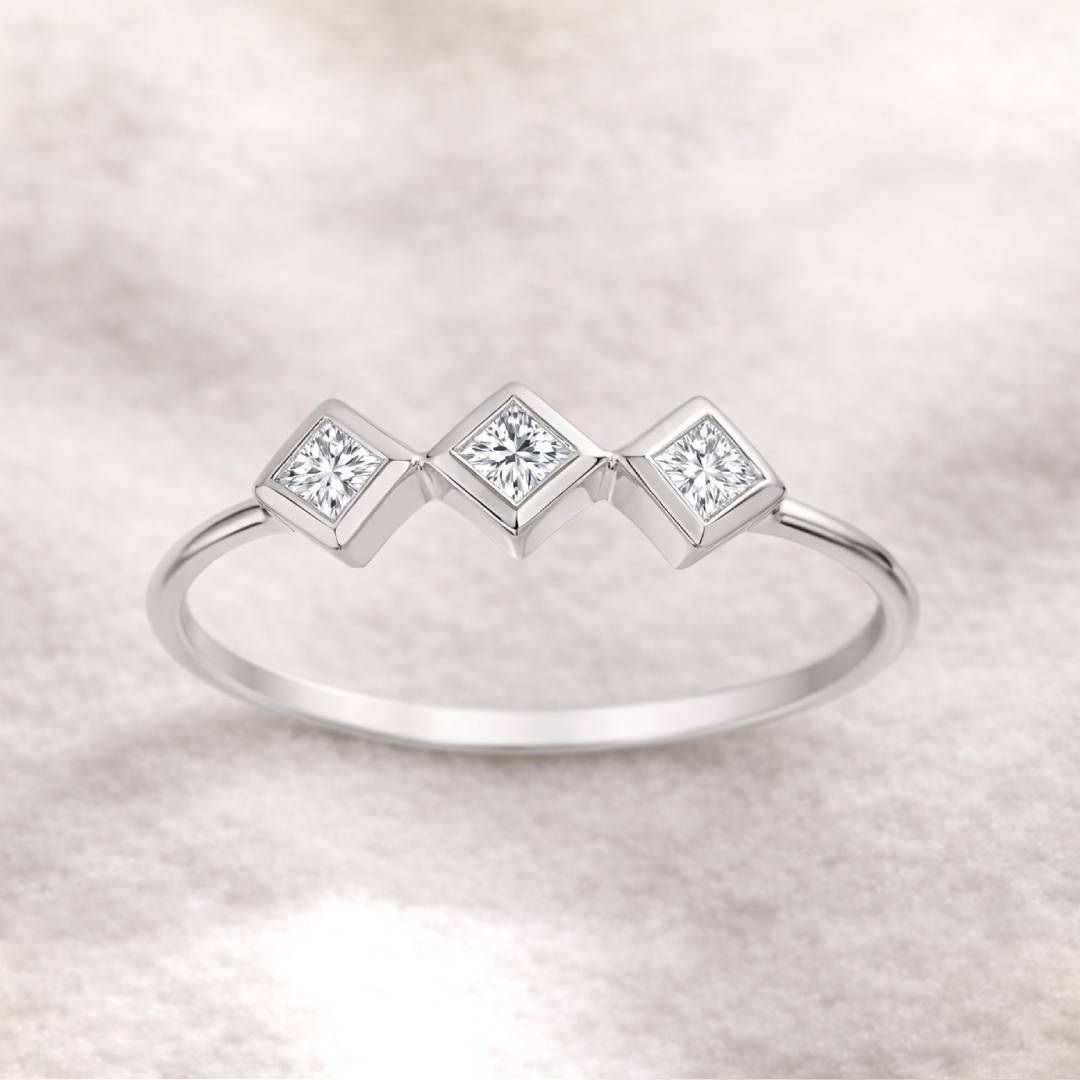 ring with three square-cut gemstones on a light background