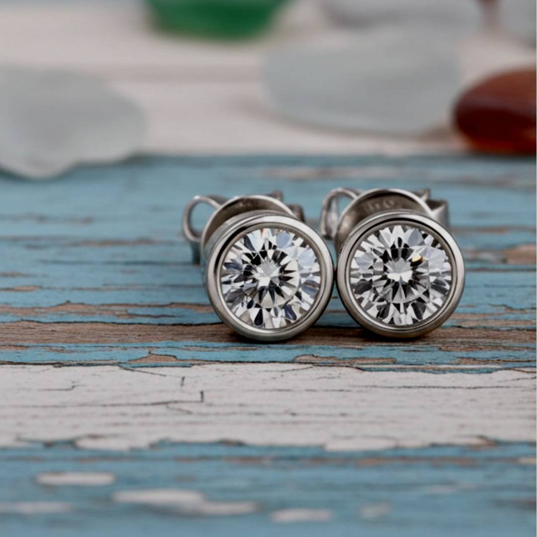 Pair of stud earrings with clear gemstones on a rustic wooden surface.