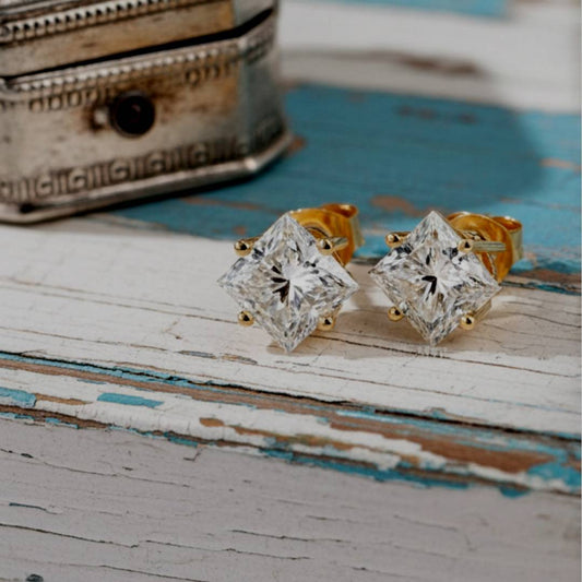 Gold diamond stud earrings on a rustic wooden surface