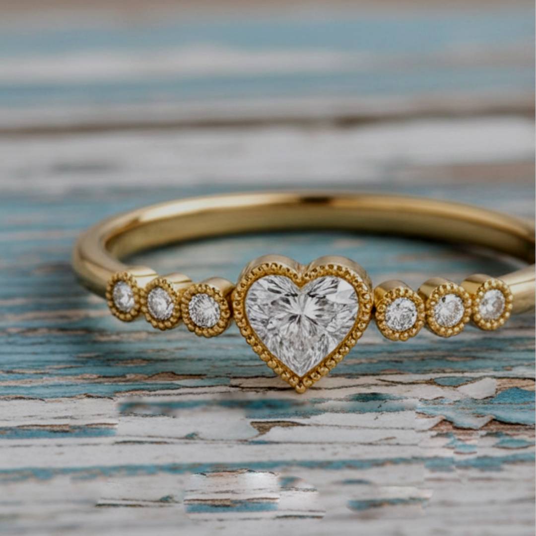 Gold ring with a heart-shaped diamond on a textured surface