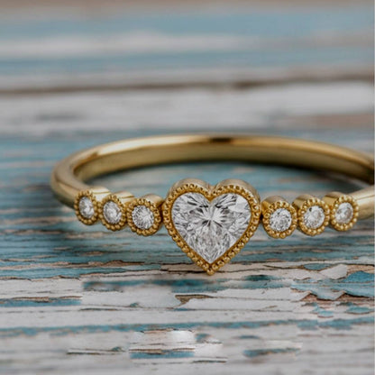 Gold ring with a heart-shaped diamond on a textured surface