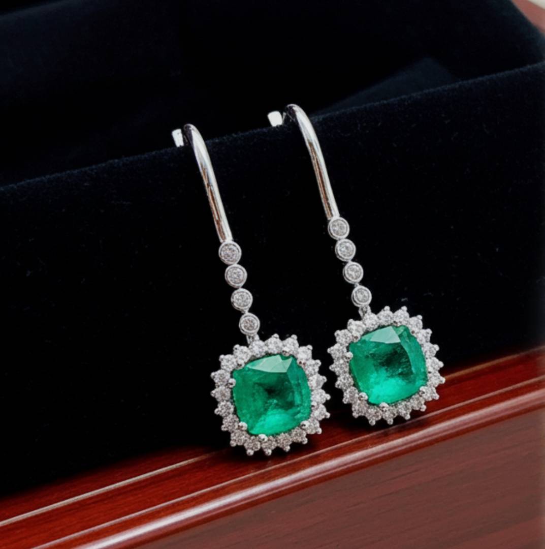 Pair of emerald earrings with diamond accents on a dark background