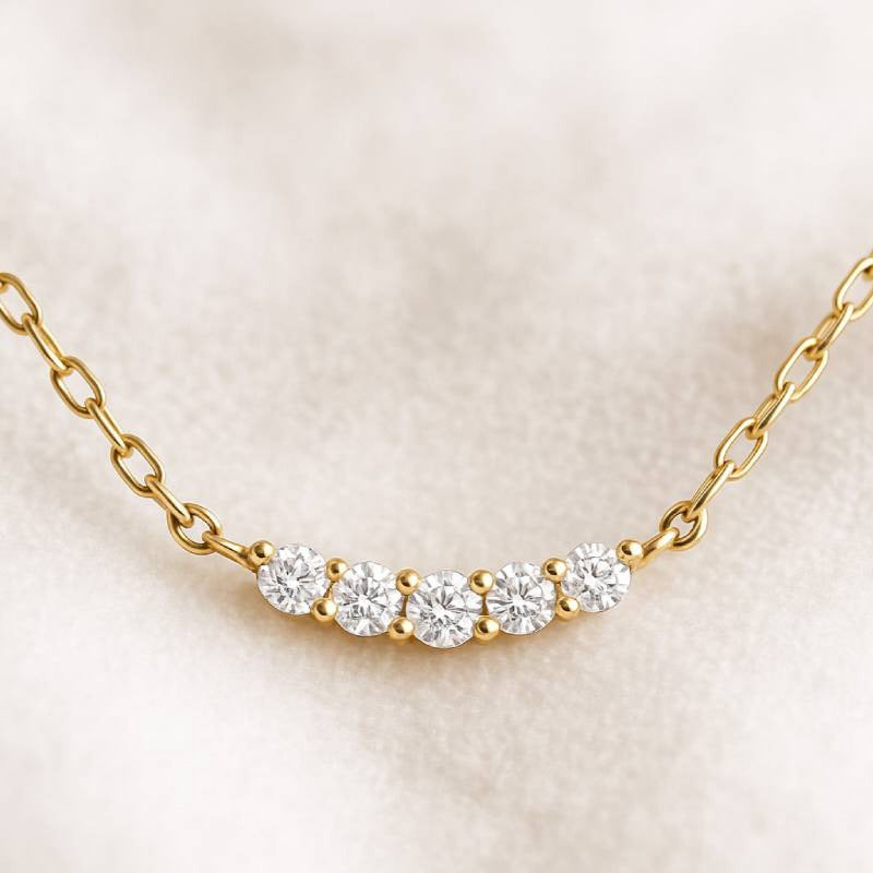 Gold necklace with clear stones on a beige background