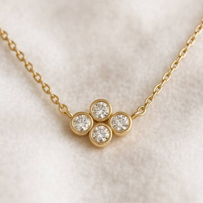 Gold necklace with four round diamonds on a light background