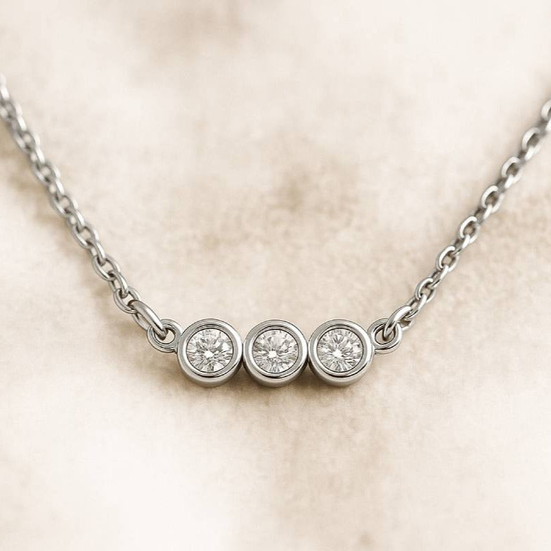 necklace with three round diamonds on a beige background