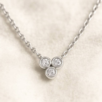 necklace with three round diamonds on a light background
