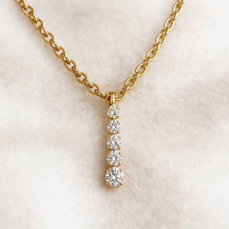 Gold necklace with a diamond pendant on a light background