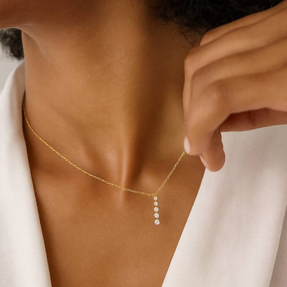 Gold necklace with a small pendant being adjusted on a person's neck.