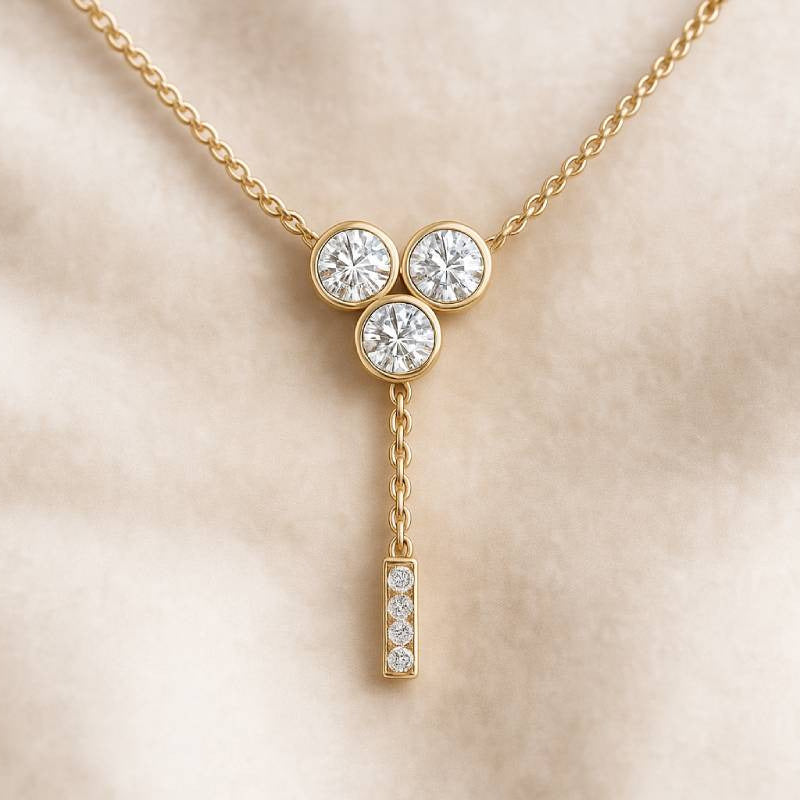 Gold necklace with three round diamonds on a beige background