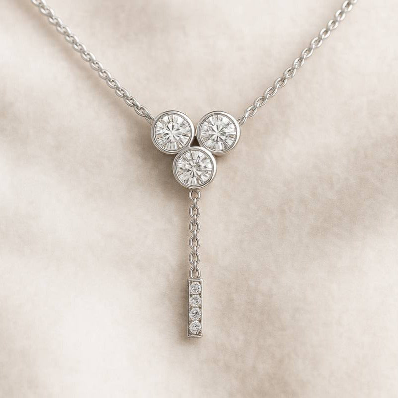 necklace with three round diamonds and a hanging bar on a beige background