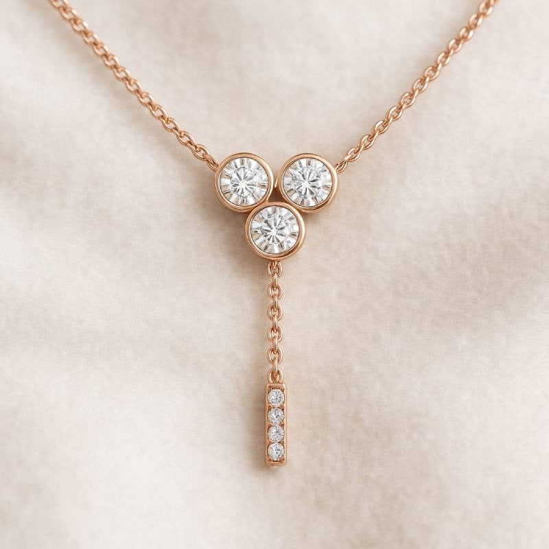 Rose gold necklace with three round diamonds on a beige background