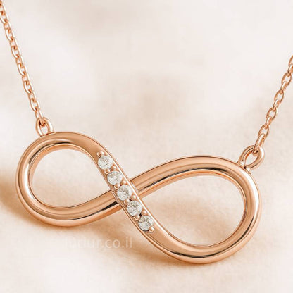 Rose gold infinity necklace with diamonds on a beige background