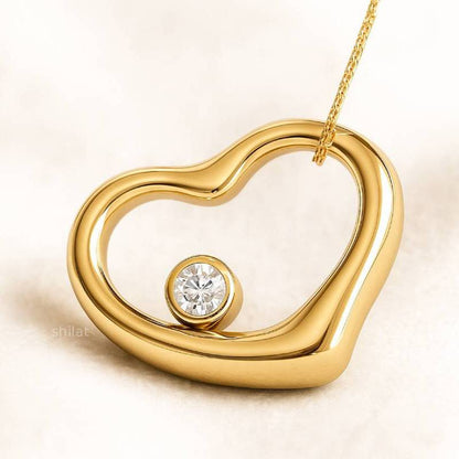 Gold heart-shaped pendant with a diamond on a beige background