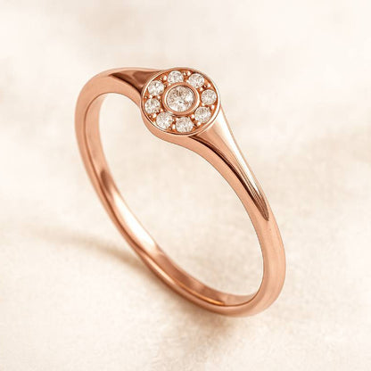 Rose gold ring with diamond accents on a beige background