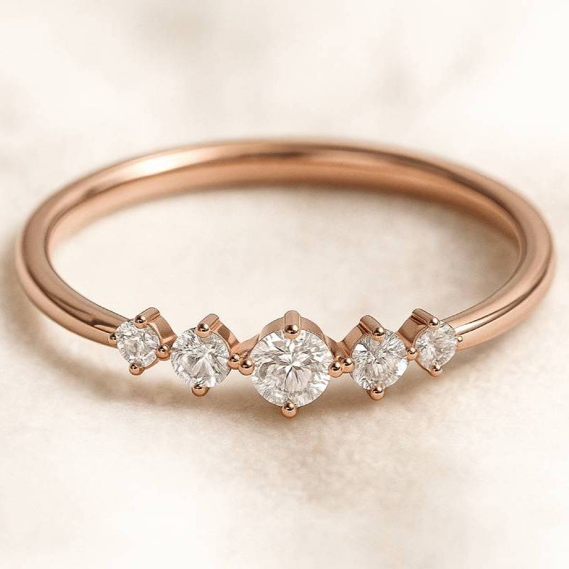 Rose gold ring with five diamonds on a beige background