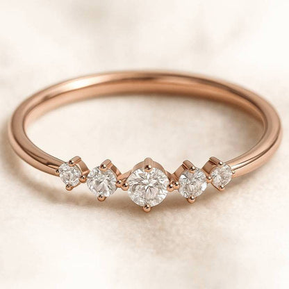 Rose gold ring with five diamonds on a beige background