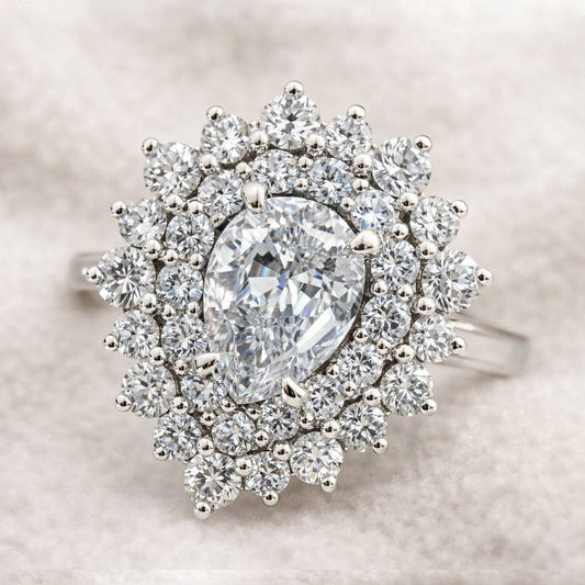 Diamond ring with a pear-shaped center stone on a neutral background