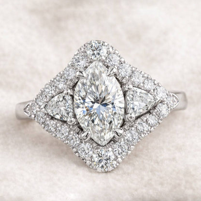 Diamond ring with pear-shaped center stone on a soft beige background