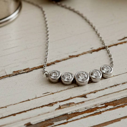 necklace with five round diamonds on a wooden surface
