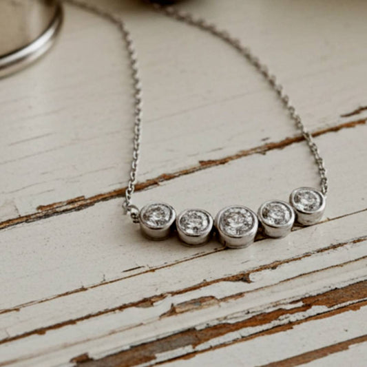 necklace with five round diamonds on a wooden surface
