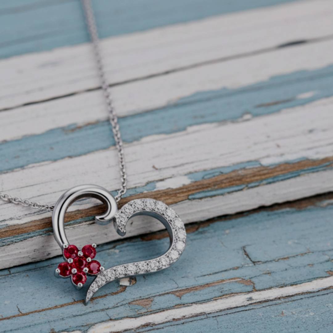 necklace with a heart and flower pendant on a wooden surface