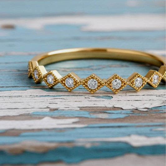 Gold ring with diamond-like stones on a rustic wooden surface