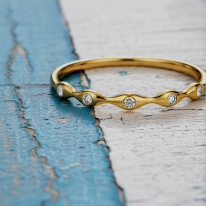 Gold ring with diamond accents on a textured blue and white surface