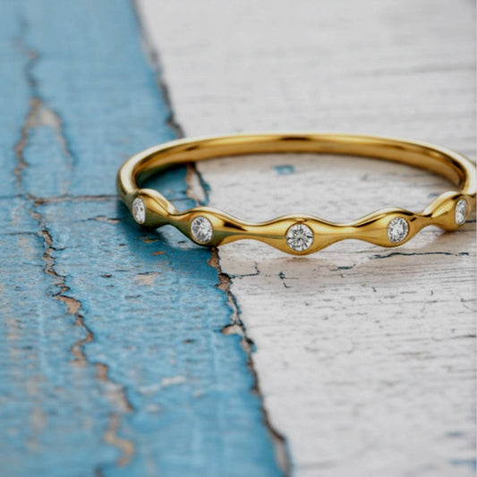 Gold ring with diamond accents on a textured blue and white surface