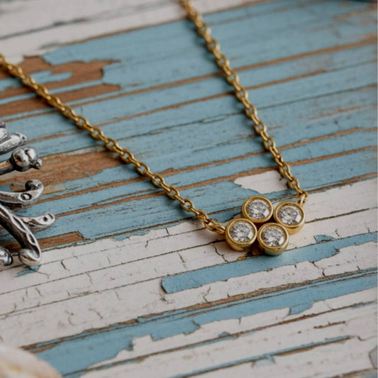 Gold necklace with a floral design on a rustic wooden surface