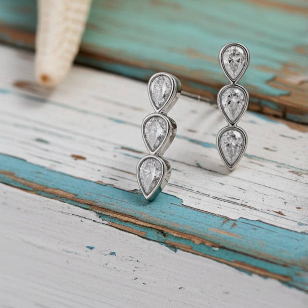 teardrop earrings on a rustic wooden surface with blue and white paint.