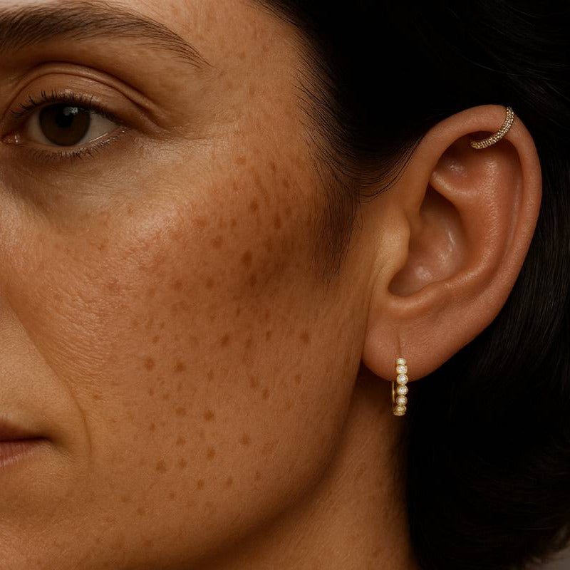 Close-up of a person's ear with earrings and skin texture.
